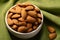 Eco conscious snack almonds on canvas napkin, green background perfection