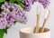 Eco friendly bamboo toothbrush in a cup with lilac flowers on white