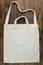 Eco friendly canvas shopping white bag on the dark wooden table background. Top views with clear space