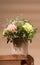 Eco friendly composition with flowers bouquet in DIY carton vase standing on old wooden table on beige with copy space