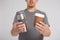eco friendly concept - young man comparing thermo cup with disposable paper coffee cup over grey background