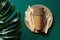 Eco friendly craft paper tableware on green background with monstera leaf