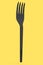 Eco-friendly disposable utensils like fork on yellow background.