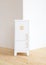 Eco-friendly minimalist style toy furniture. White wooden play fridge in empty white room copy space