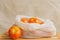 Eco friendly and no plastic. Reusable Cotton Mesh Bag full of tomatoes isolated on beige on top of a wooden fruit box