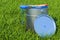 Eco-friendly paint concept. Can with paint and brush in the green grass, 3D rendering