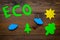 Eco icon cutout near environment symbols as sun, trees, clouds on dark wooden background top view