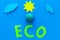 Eco icon cutout near plastiline symbol of planet Earth, sun, clouds on blue background top view copy space
