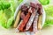 Eco paper bag with mediterranean snack closeup. Fuet, chorizo sausages, jamon and bread sticks on the natural fresh lettuce