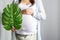 Eco pregnancy. Pregnant woman with big belly advanced pregnancy holding green tropical palm monstera leaf in hand.