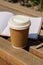 Eco recycling paper cup with coffee or tea on kraft paper with empty paper notebook on wooden bench. Concept of study