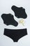 Eco sanitary reusable pads with white delicate flower and black underpants on grey background. Health care and zero-waste, no