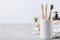 Eco toothbrushes. Bamboo toothbrushes cup, natural soap, plastic free ear sticks, wooden hair brush and white towels on gray