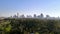 Ecological contrast: cityscape with skyscrapers against a green park with green trees. aerial view 4K