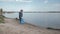 Ecological purification of nature, child boy pulls heavy bag of trash on pointing sign on river beach after cleaning up