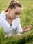 Ecologist or biologist in a white coat and glasses examining plants