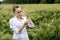 Ecologist or biologist in a white coat and glasses examining plants