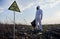 Ecologist standing in field with garbage and biohazard sign.