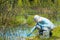 The ecologist takes a sample of water from a forest reservoir