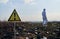 Ecologist walking in garbage dump field with warning sign.