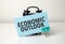 economic outlook is written in a blue sticker near a black alarm clock