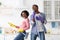 Ecstatic black couple imitating rock stars while cleaning house