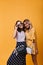 Ecstatic girl in long skirt touching her white sunglasses while posing with best friend. Indoor photo of compelling