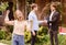 Ecstatic millennial woman with house key and her boyfriend shaking hands with real estate broker in backyard