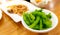 Edamame or green soybeans blanched in white bowl on wooden table at Japanese restaurant. Pods of green soy beans on blurred