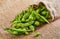 Edamame or soybeans spill out of the bag onto a brown sackcloth