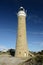 Eddystone Point Lighthouse highlighted by sunshine against rich blue sky