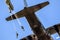 EDE, NETHERLANDS - SEP 21, 2019: Military paratroopers parachute jumping out of a Air Force C-130 Hercules transport plane during