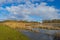 Edge of a canal in a green grassy landscape in wetland in sunlight under a blue sky in winter