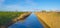 Edge of a canal in a green grassy landscape in wetland in sunlight under a blue sky in winter