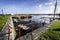 Edge of dirty Lake with small boats with bright blue sky