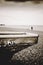 Edge of old wooden boat with lonely female figure on pebble beach and remains of the west pier in distance and overcast sky, Brig