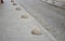 The edge of the sidewalk formed by concrete bollards in the shape of a hemisphere or a gray lens used to prevent cars from