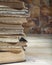 The edge of a stack of old books recumbent on a wooden table. Close-up