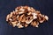 Edible dried mushrooms pile black wooden background close up, dry boletus edulis heap dark wood backdrop chopped brown cap boletus