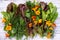 Edible greenery and orange flowers nasturtium on a white wooden background. top view.