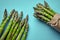 An edible, raw stems of asparagus on blue background.