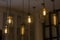 Edison`s antique lamps of various shapes and sizes in lampshades glow in the dark under the ceiling