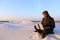 Educated Arab student uses laptop and works sitting on sand amid