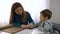 Education of blind children, mother teaches child boy to write braille sitting at table in bright room