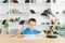 Education, childhood, people, homework and school concept - smiling student boy with book writing to notebook at home