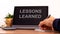 Education concept. Tablet with text `lessons learned`. Online education during COVID-19 quarantine. Male hand with pen, calculat