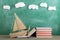 Education is a journey concept, toy boat and books on the chalkboard background, inspiration for a fairy tale