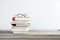 Education, personal development and study concept with eyeglasses on stack of books on wooden table surface and white wall