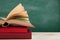 Education and reading concept - group of colorful books on the wooden table in the classroom, blackboard background