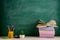 Education and reading concept - group of colorful books on the wooden table in the classroom, blackboard background